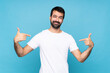 © luismolinero - Young man with beard  over isolated blue background proud and self-satisfied