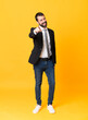 © luismolinero - Full-length shot of business man over isolated yellow background points finger at you with a confident expression