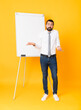 © luismolinero - Full-length shot of businessman giving a presentation on white board over isolated yellow background having doubts while raising hands