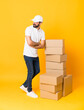 © luismolinero - Full-length shot of delivery man among boxes over isolated yellow background with arms crossed and happy