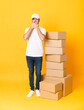 © luismolinero - Full-length shot of delivery man among boxes over isolated yellow background covering mouth with hands