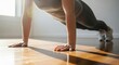 © Assetian - A person doing push ups on a wooden floor in a well lit room with sunlight
