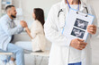 © Pixel-Shot - Female fertility doctor with sonogram image of couple after IVF in clinic