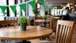 © alsu0112 - Wooden table set for St. Patrick's Day celebration with green bunting and potted plant in a cozy restaurant interior featuring wooden chairs and warm lighting