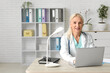 © Pixel-Shot - Mature female doctor working with laptop at table in clinic