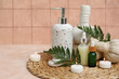 © Pixel-Shot - Set of spa supplies with bottles of cosmetic oil, herbal bags, fern branches and burning candles on beige table