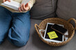 © juliasudnitskaya - Digital detox concept from woman reading paper book while phone and tablet gadgets lying offline in basket. Home and mental leisure instead social media and technology addiction.