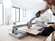 © JARVIS X - Professional Caucasian Man Cutting Ceramic Tile with Tile Cutter During Home Renovation Project in Modern Apartment with Copy Space