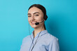 © New Africa - Portrait of smiling hotline operator in headset on light blue background