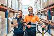 © Santi Nuñez/Stocksy - Warehouse workers smiling and holding tablet and clipboard