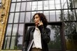 © Studio Sincère/Stocksy - Woman Talking on Phone Outside a Modern Building