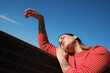 © JORGE PONZ/Stocksy - Woman relaxing against a wall under clear blue sky
