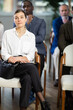 © JackF - Adult woman sits in conference room or office with colleagues and listens to lecture and watching presentation