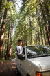 © Meg Pinsonneault/Stocksy - Man Sitting on Van Window Parked Among Giant Redwood Trees