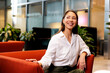 © Artem Podrez/Stocksy - Business Casual Woman Relaxing on Red Chair in Office Lounge