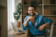 © Miljan Živković - Man smiling working from home office on laptop