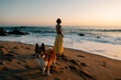 © Maria Sher/Stocksy - Woman Enjoys Sunset Walk on the Beach With Her Dog