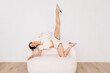 © Tania Cervian/Stocksy - Woman posing on sofa with flexibility