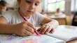 © Toma Hieu - Close up of a focused little girl drawing with a pink crayon in a notebook at kindergarten