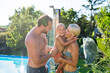 © Halfpoint - Family under shower by the pool on sunny summer day.