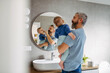 © Halfpoint - Morning routine in bathroom, father brushing sons teeth.
