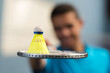 © auremar - closeup of shuttlecock on racket held by young man