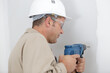 © auremar - mature tradesman using drill on interior wall