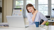 © matinee - Young businesswoman feeling neck pain while sitting at desk, experiencing muscle strain from long hours of computer work.