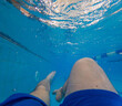 © phpetrunina14 - Underwater pov of swimmer legs in blue pool Copy Space