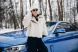 © Petro - Young woman standing outside her car in winter