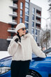 © Petro - Young woman standing outside her car in winter