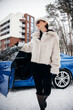 © Petro - Young woman standing outside her car in winter