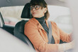 © olezzo - Mature business woman in blazer and eyeglasses looking back while driving or parking car