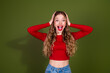 © deagreez - Energetic young woman in red top with long blonde hair smiles widely against a green studio backdrop