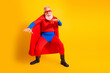 © deagreez - Senior superhero performer in red cape blue suit and mask strikes a dynamic pose against a bright yellow backdrop