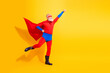 © deagreez - Senior superhero character in bright red and blue costume strikes a dynamic pose with cape against a yellow backdrop