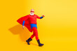 © deagreez - Senior superhero in red costume with cape and mask dancing on a bright yellow background for fun and entertainment