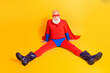 © deagreez - Senior bearded man as a superhero with red cape and blue shorts sits on bright yellow background for fun halloween photo promotion