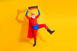 © deagreez - Dancing senior superhero in red and blue costume leaps with a boombox against a bright yellow background