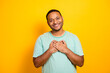 © deagreez - Happy mixed man smiles with hands over heart against bright yellow background in a casual lifestyle portrait suitable for advertising shopping and branding use