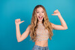 © deagreez - Young stylish woman in checkered crop top and jeans posing with thumbs up smiling against blue background