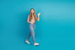 © deagreez - Casual chic teen girl smiling waving against blue background wearing jeans and patterned top