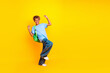 © deagreez - Happy young boy with backpack jumping against bright yellow background