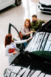© djile - Saleswoman showing car exterior features to interested couple