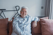 © Daniel - Elderly man sits on a sofa at home smiling at the camera. He appears cheerful and relaxed while enjoying his peaceful domestic environment.