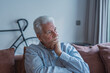 © Daniel - A sad elderly man sits alone on a sofa at home, looking out the window with a worried expression while reflecting on life challenges, stress, and the emotional weight of loneliness