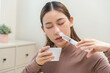 © KMPZZZ - Health care wash nose, cleaning nose concept. Nasal irrigation asian young woman illness have a flu, fever, have a runny nose. Girl washes out nose with syringe and saline, infection, dust allergic.
