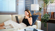© Stella 16 - Happy young woman with coffee cup and tablet lie down on couch in living room at home