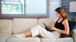 © Stella 16 - Woman relax on couch with tablet, online streaming with internet and reading ebook or watching film at home. Happy female person with technology, subscription and mobile app with break in living room
