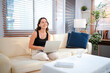 © Stella 16 - Laptop, young woman and working from home with a smile writing for website. Happy freelancer, living room sofa and female person blogging on a lounge couch and typing a blog post on a computer